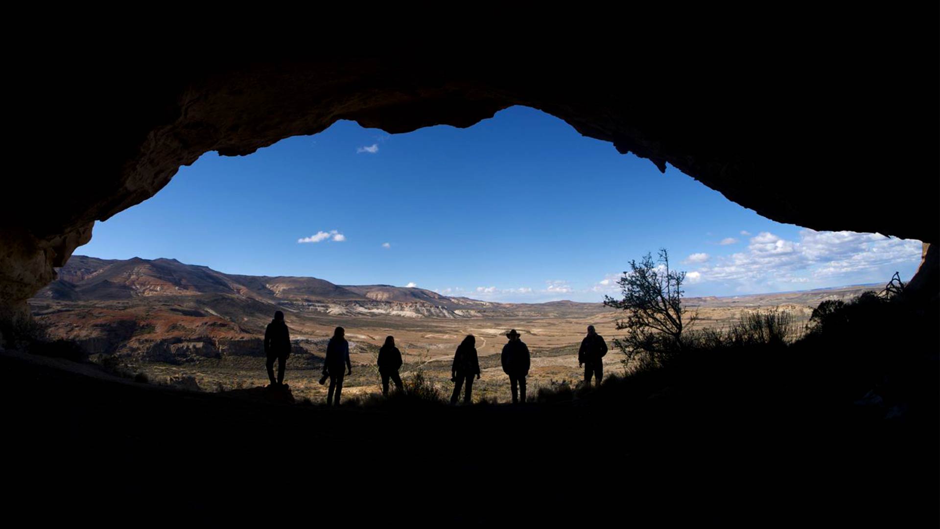Photographers inside a cave at Los Toldos with cave paintings at Tierra Salvaje Luxury Patagonia Archaeology Exploration