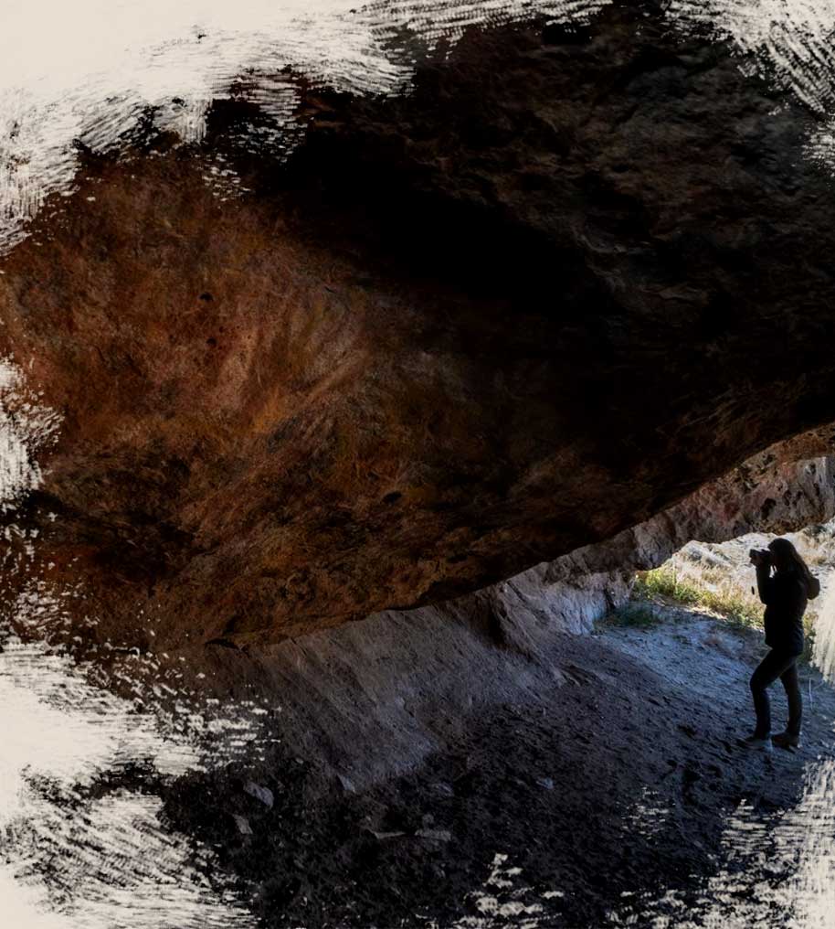 Photographer inside Cave at Los Toldos Santa Cruz looking at Hand Imprint Pictures from Tehuelches a Luxury Archaeological Experience Patagonia Argentina